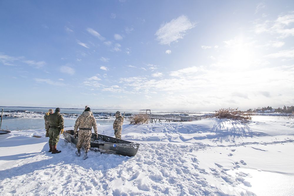 Camo outfitted hunters and canoe in the snow