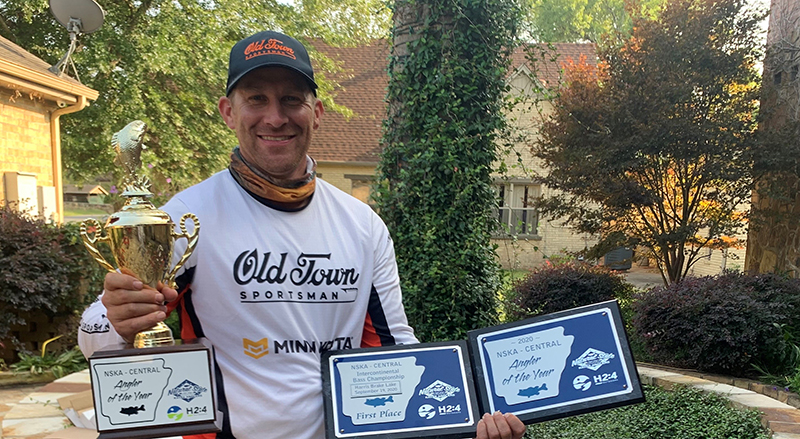 Garrett Morgan poses with a trophy and three plaques wearing an Old Town jersey. 