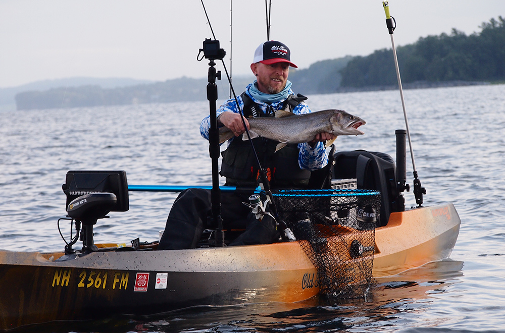 Tim Moore holding a lake trout on his orange Old Town Sportsman AutoPilot 136