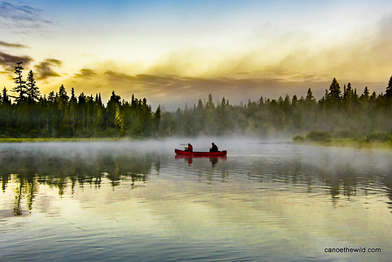 A canoe on calm water with fog. 