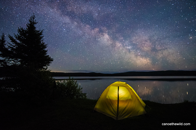 Milky Way on the Allagash River, with a glowing tent in the foreground. 