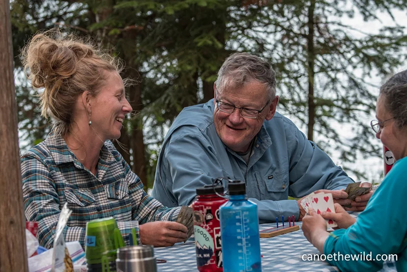 Maine guide Tammi Matula playing cards with canoe guests after a day's paddle and hearty meal. 