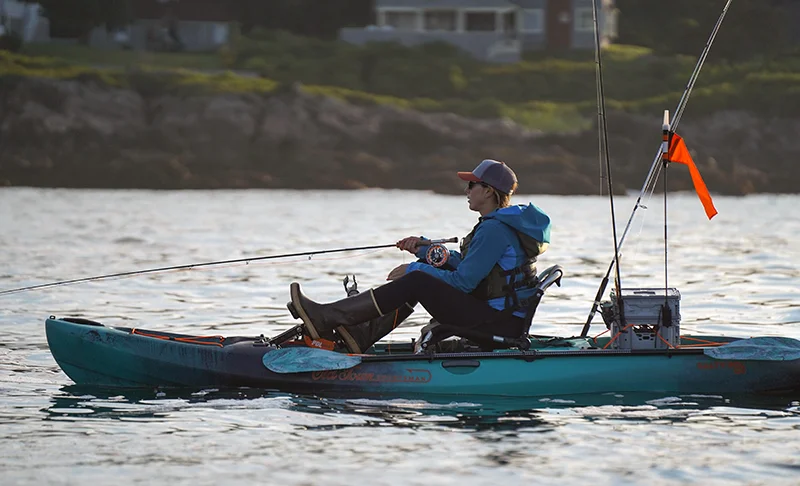 Christi Holmes sits on a pedal kayak and retrieves a fly while targeting Striper 