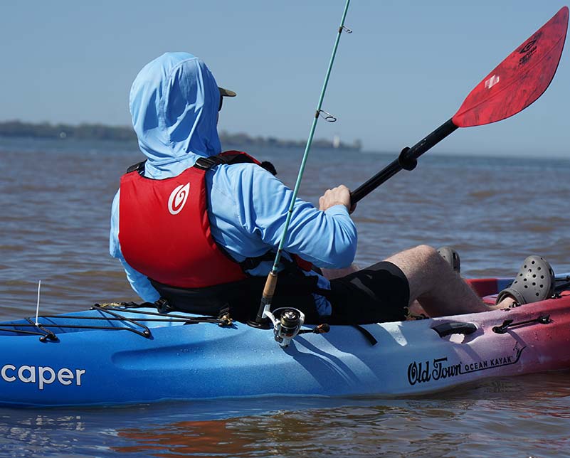 Man paddling in the Old Town Ocean Kayak Caper wearing Outfitter Universal Life Jacket