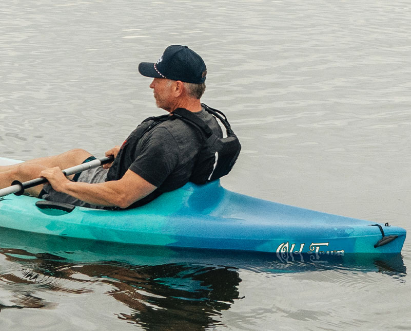 Man in Old Town Breeze kayak on the water with close up of molded seat and tankwell