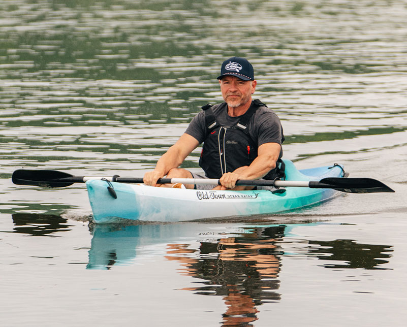 Man relaxing in the Old Town Breeze recreational kayak on the water with Carlisle day tripper paddle in hands