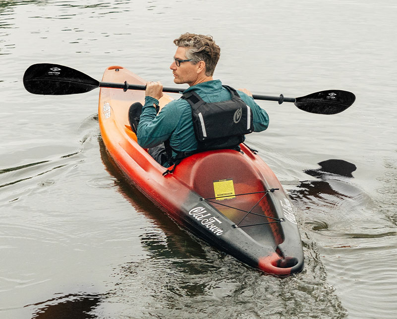Man paddling in Old Town Twister recreational kayak with large tankwell and Carlisle paddle in hand