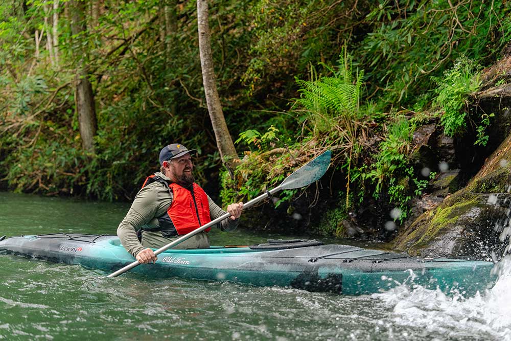 Man paddling in Old Town Loon 126 recreational kayak wearing the Riverstream life jacket