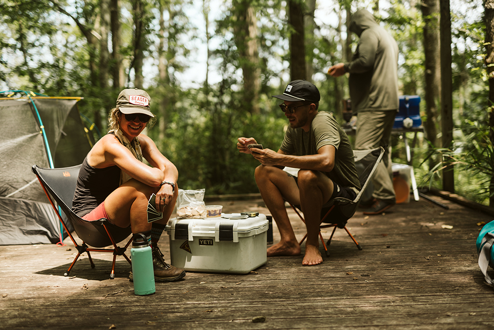 Paddlers relax in camp chairs on their tent platform and play a game of cards before turning in for the night. 