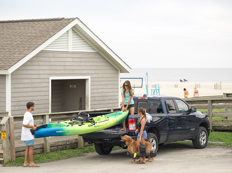 A small group of kayakers remove a kayak from a truck bed.