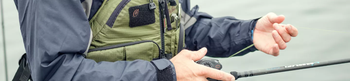 Close-up of a man in a green life jacket holding a fishing rod