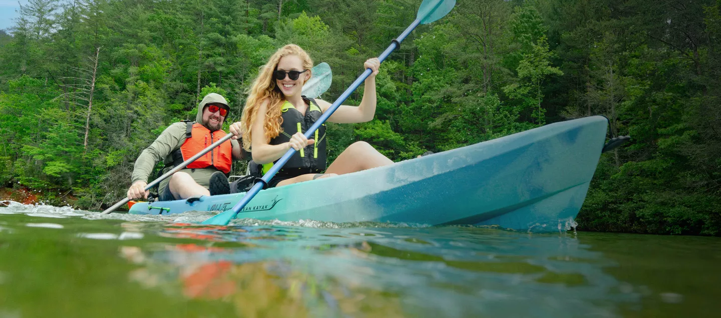 Two kayakers in a blue Ocean Kayak tandem sit on top kayak.