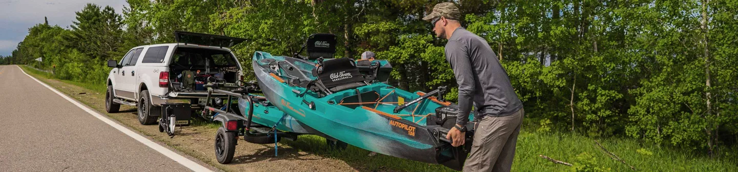 Loading Old Town Sportsman AutoPilot 136 kayaks onto Malone kayak trailer on back of truck