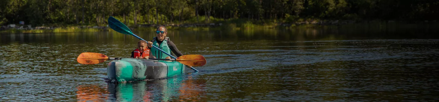 A mother and son paddling a tandem Old Town kayak.