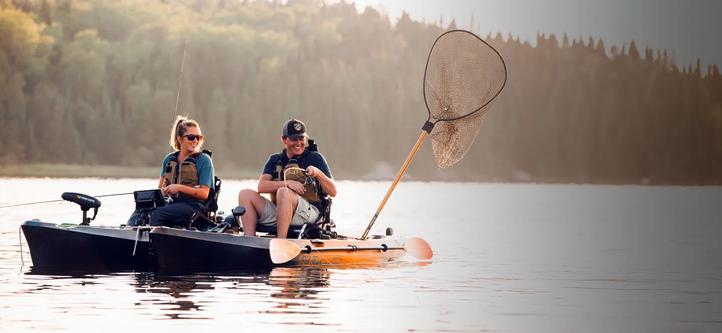 Man and Woman in Old Town Sportsman AutoPilot 120 and PDL 120 fishing kayaks catching fish