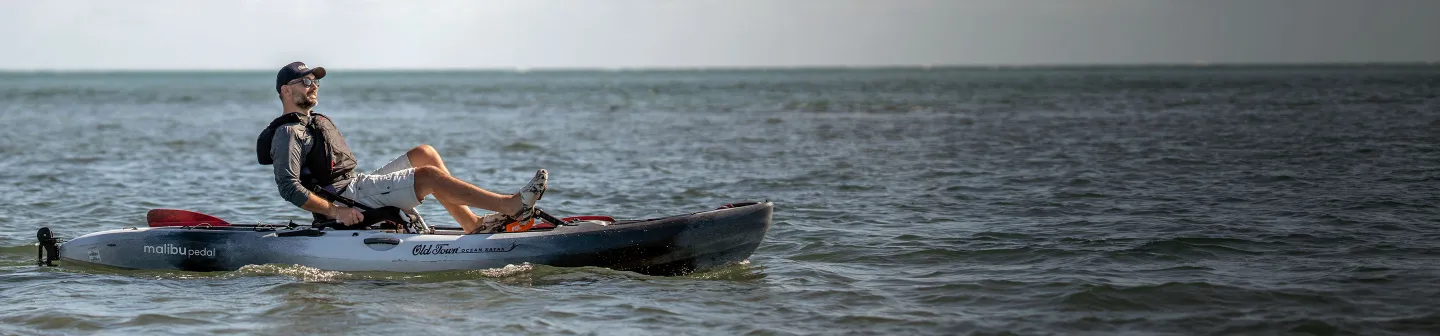 Man happily pedaling in Old Town Ocean Kayak Malibu Pedal wearing Carlisle life jacket