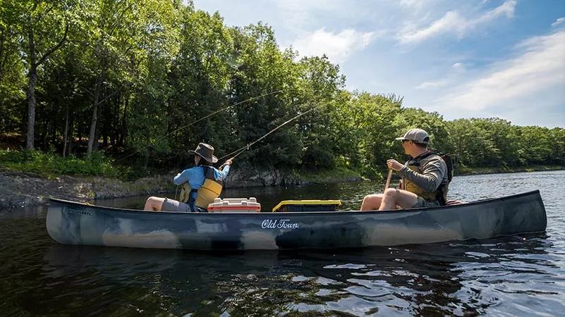 Couple in camo Old Town Discovery canoe fishing in a small lake