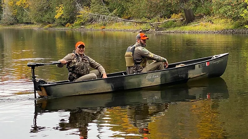 Two men in the Old Town Discovery Sport 15 hunting canoe with minn kota motor attached