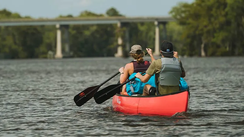 Man and Woman paddling in an Old Town Discovery canoe on a lake