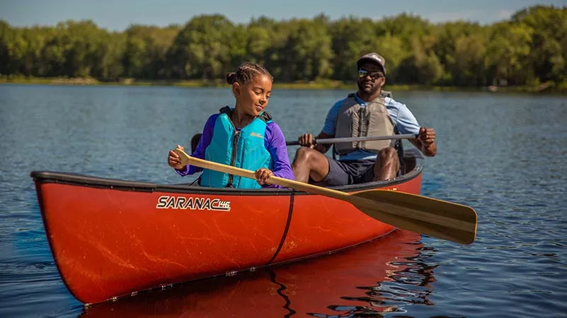 Man and daughter happily paddling in the Old Town Saranac 146 recreational canoe