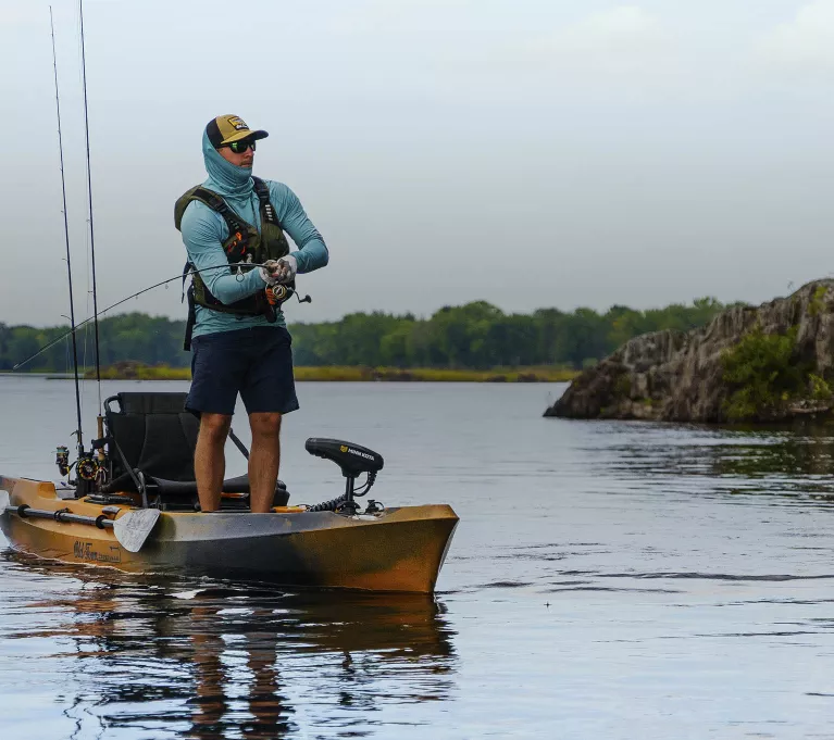 A man stands and casts from a Sportsman fishing kayak.