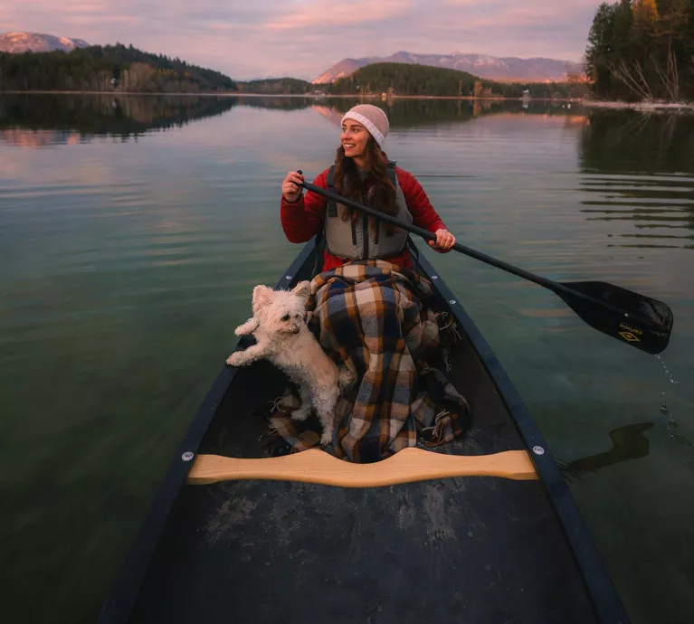 Smiling Woman paddling with Dog in Old Town Discovery Canoe