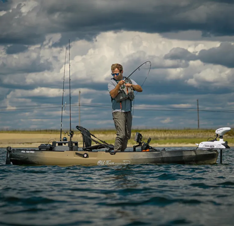 Man standing up and fishing in the Old Town Sportsman PDL 120 Pro fishing kayak with kayak terova riptide