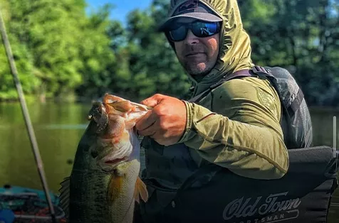 Brandon Singleton looks over his shoulder while holding up a big smallmouth bass.