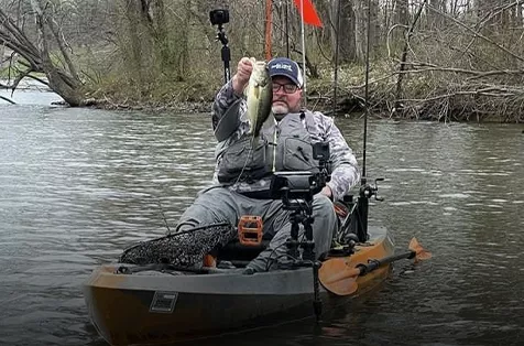 JT Hickman holds a bass in his kayak.